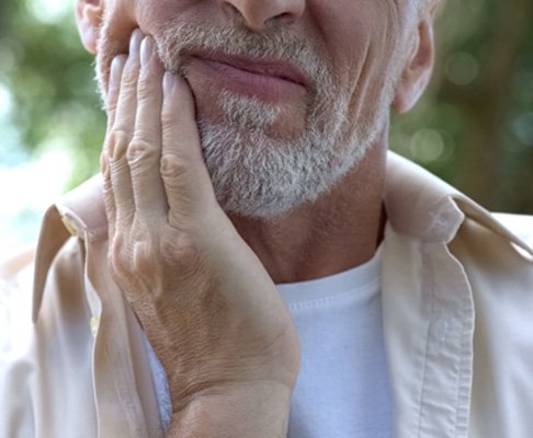 Bearded man with tooth pain rubbing his jaw
