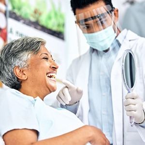 a patient checking her teeth after getting dental implants 