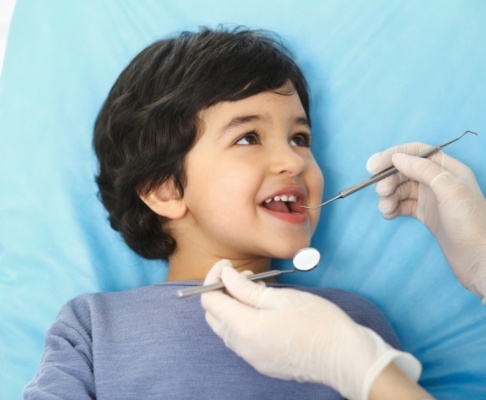 Young dental patient receiving children's dentistry checkup and teeth cleaning