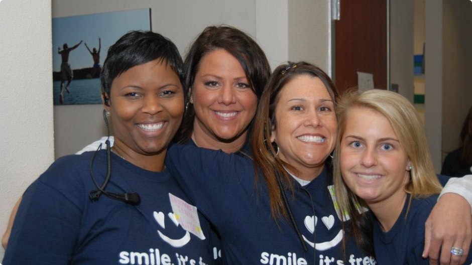 Four smiling dental team members at community event