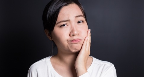 Woman with lost dental crown holding cheek in pain