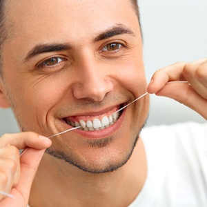 man smiling while flossing his teeth