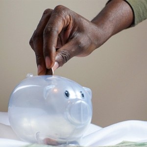 Hand putting coin in plastic piggy bank