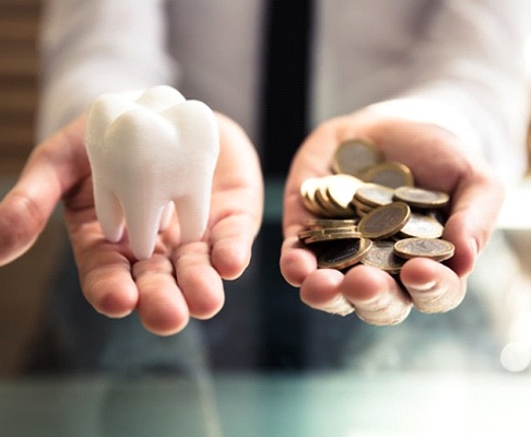 Hands holding tooth and coins representing cost of veneers in Southlake