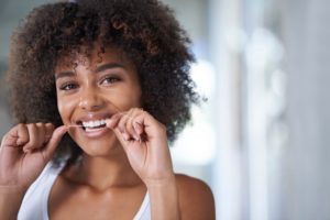 smiling woman flossing with Invisalign 