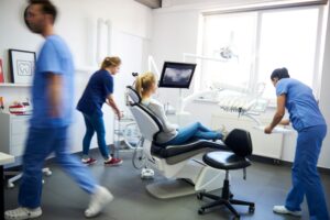 Woman in dental chair while dentists hurry around her